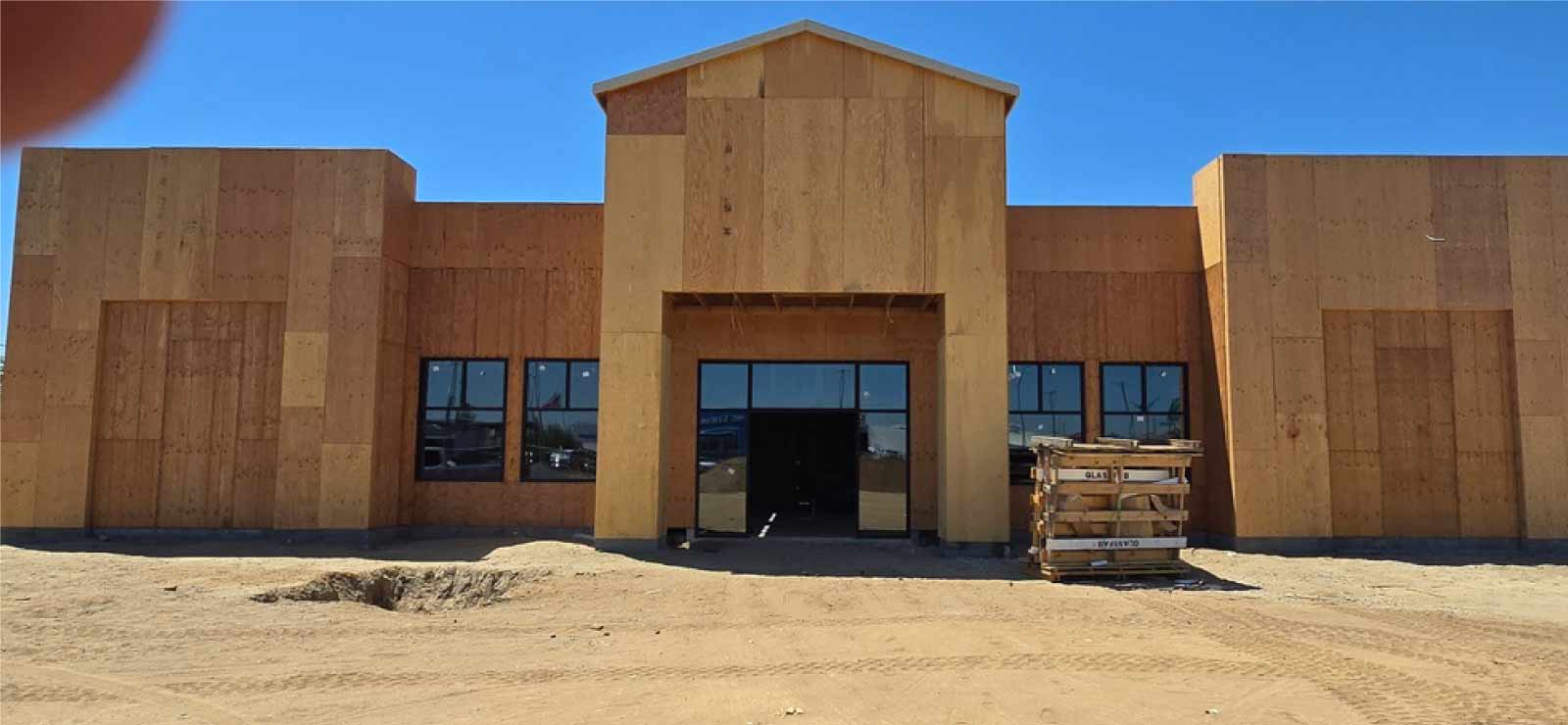 Front facade of a commercial retail building in Central Valley showing the initial construction stage with plywood sheathing installed, ready for Cal Pro Plastering’s lath and stucco application.