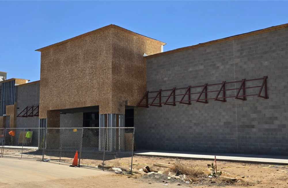 Exterior construction view of a large retail structure featuring a mix of CMU blocks and plywood framing, prepared for professional commercial plastering services.