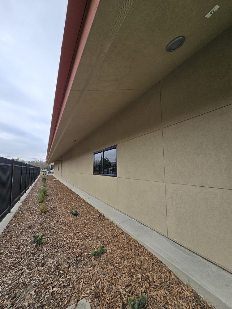 Perspective view of a long commercial building wall with uniform textured plastering and precise expansion joints.
