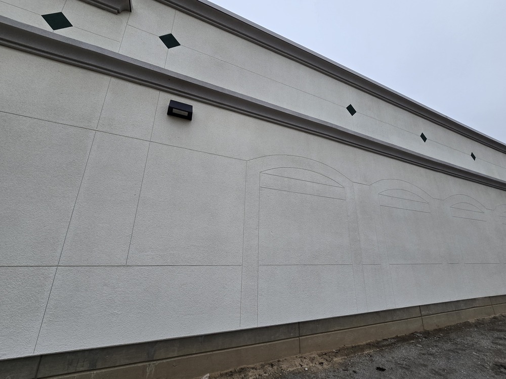 Close-up of intricate architectural plaster details and decorative recessed arches on a large commercial facade.
