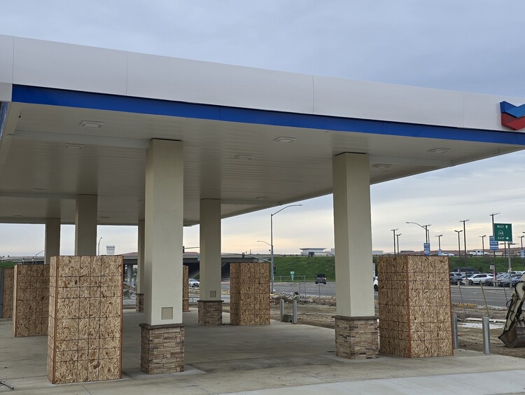 Newly plastered support columns for a Chevron gas station canopy, featuring a smooth finish and stone veneer bases.