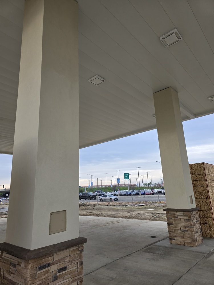 Vertical view of smooth plaster finishes on commercial canopy pillars, demonstrating a professional and polished brand identity.