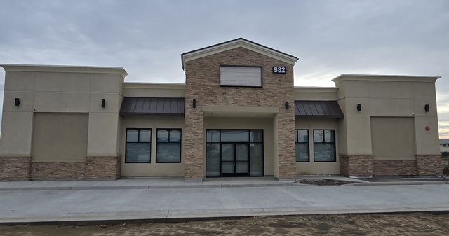 Completed commercial plastering on a multi-unit retail building, featuring a clean sand finish and architectural pilasters.