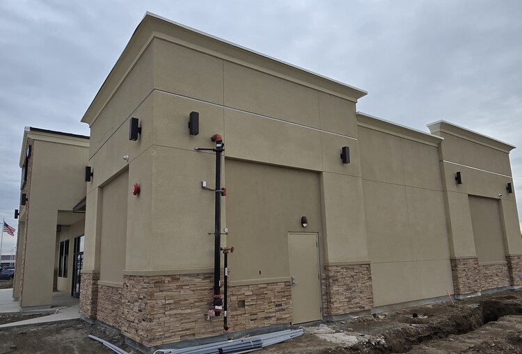 Side perspective of a retail building showcasing professional stucco application and clean interfaces with exterior utility fixtures.