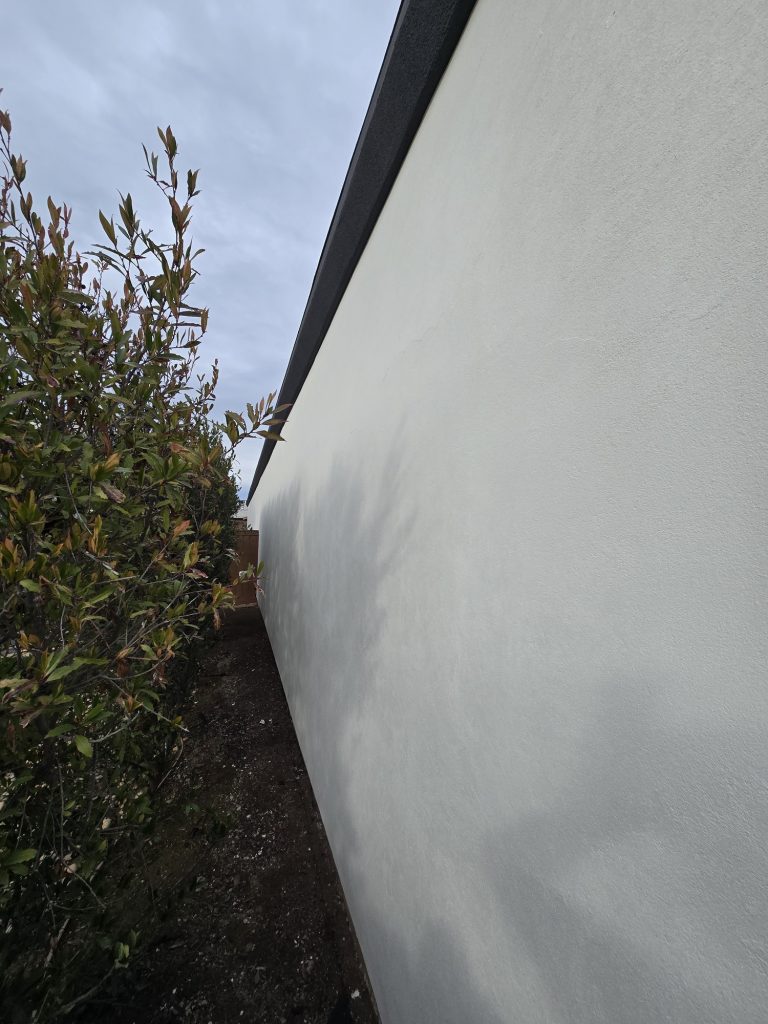 High-contrast exterior wall featuring a smooth white plaster finish against dark architectural trim for a modern commercial office.