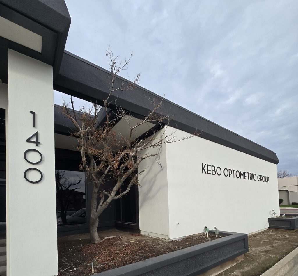 Exterior view of Kebo Optometric Group building featuring a minimalist white stucco finish and bold black metal accents.