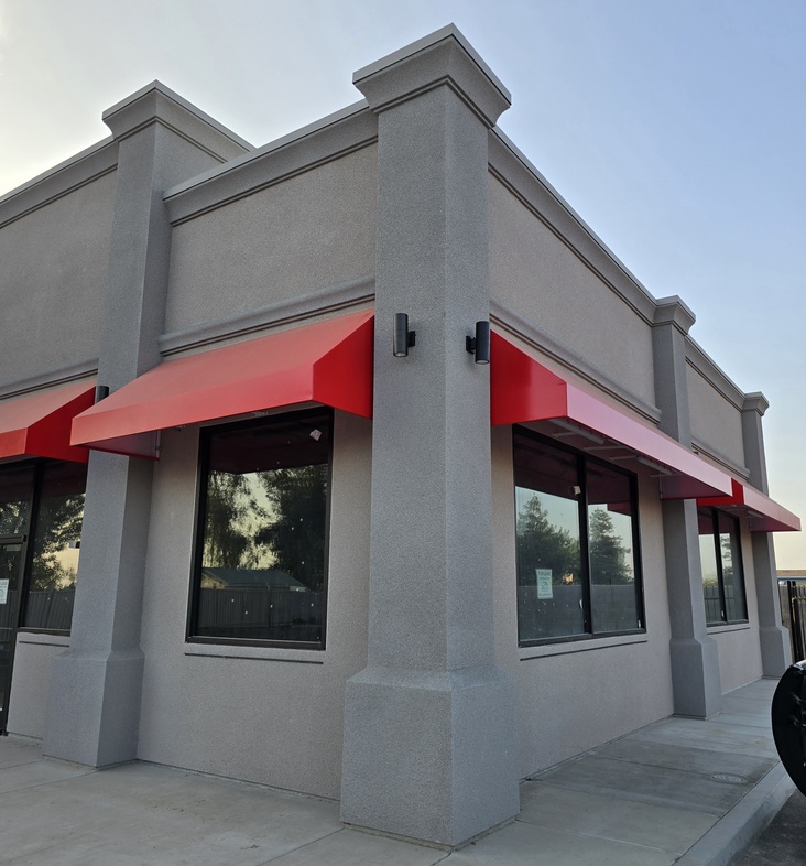 Close-up of high-quality exterior plastering work showcasing clean architectural lines and textured stucco on a modern commercial storefront corner.