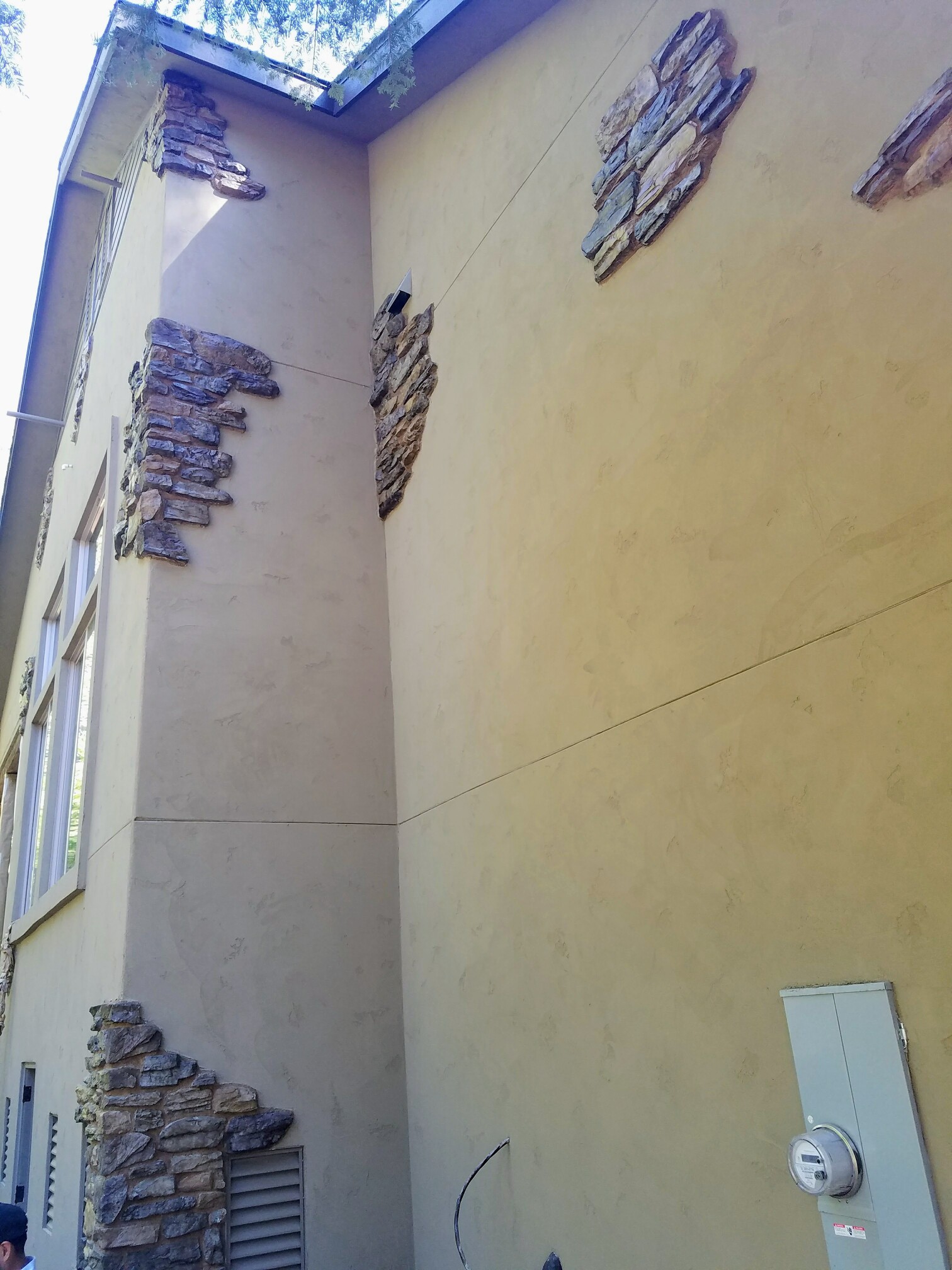 Detailed view of a custom exterior wall where smooth tan plaster meets rustic stone accents, demonstrating a warm and inviting residential atmosphere.