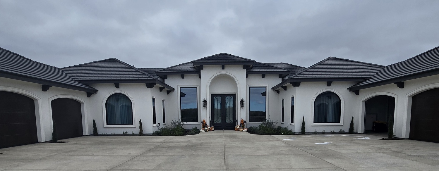 Close-up of a residential grand entrance showcasing an elegant arched plaster portico and clean stucco lines contrasted with dark wrought-iron decorative doors.